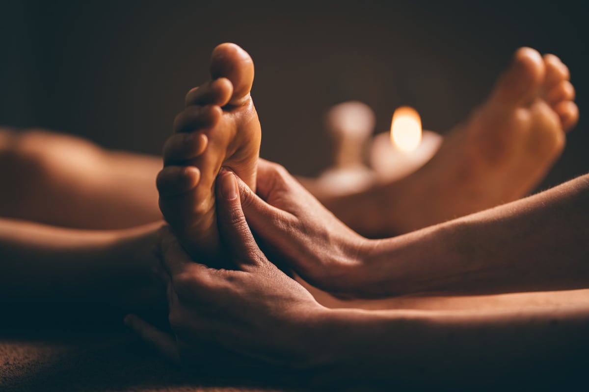 Professional foot massage close up. Authentic shot of luxury spa treatment. Charming light. Shallow depth of field. Stylized and colored.